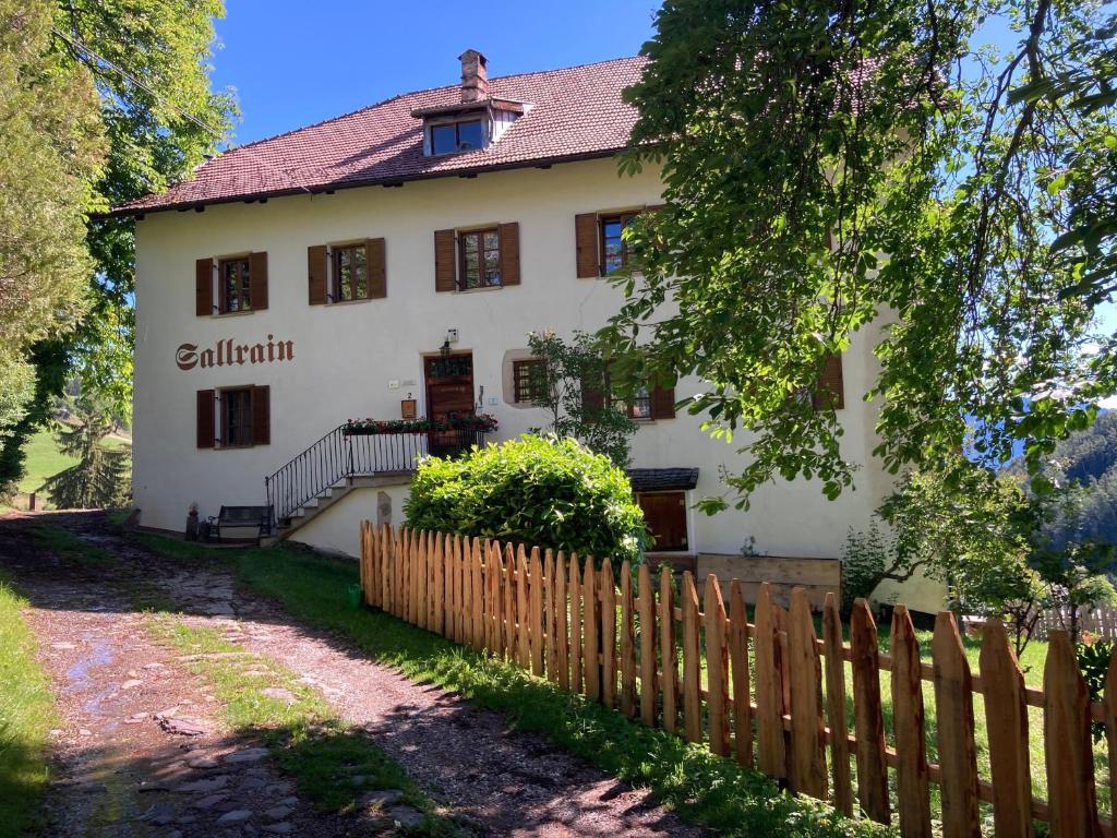 a large white house with a wooden fence at Sallrain Hof Apartment 1 in Collalbo