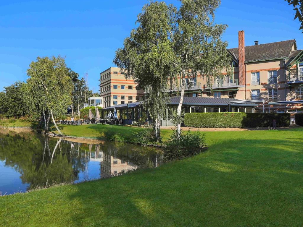 a building and a river in front of a building at Mercure Orléans Portes de Sologne in Ardon