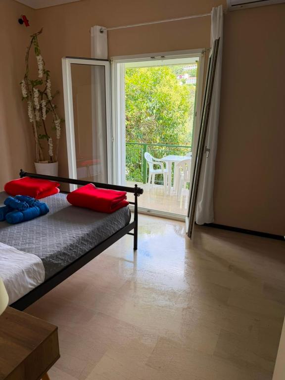 ein Schlafzimmer mit einem Bett mit roten Kissen und einem Balkon in der Unterkunft Ipsos apartment in Ýpsos