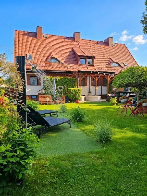 a large house with a green yard with benches at PROMYK - Apartamenty & Pokoje - dla dorosłych in Białogóra