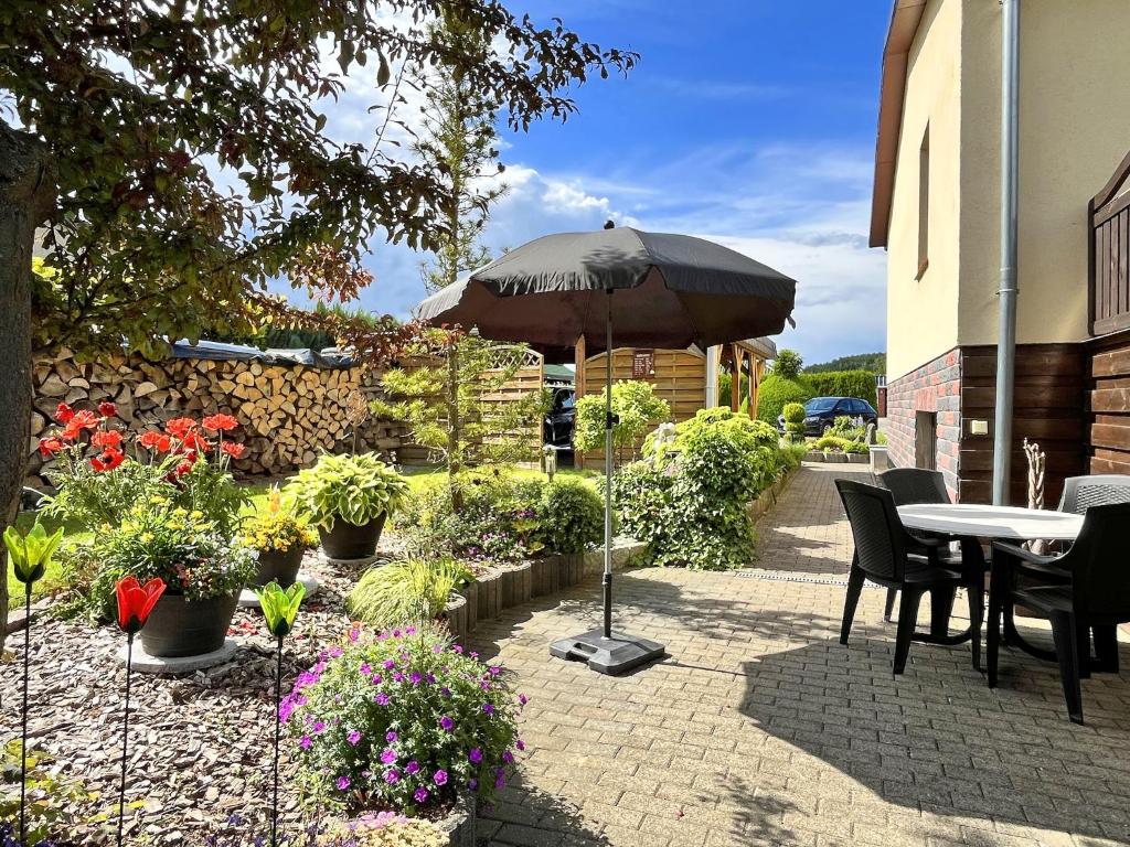 a patio with a table and an umbrella and flowers at Damshagen Küstenkomfort in Damshagen