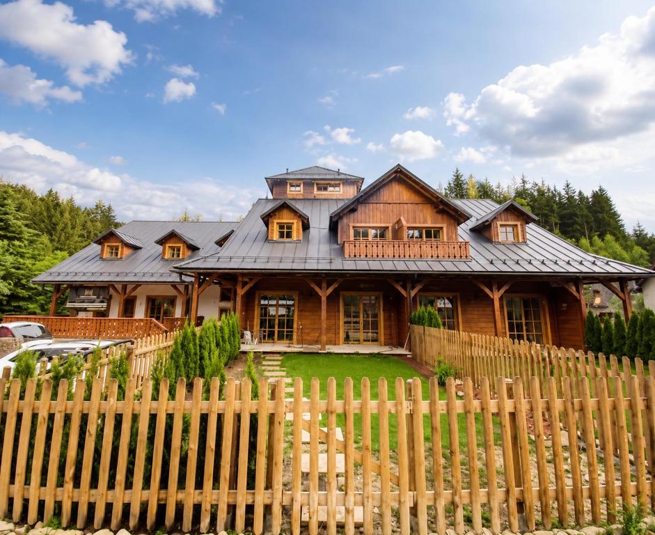 a wooden house with a fence in front of it at Apartmán Jezerné in Velké Karlovice