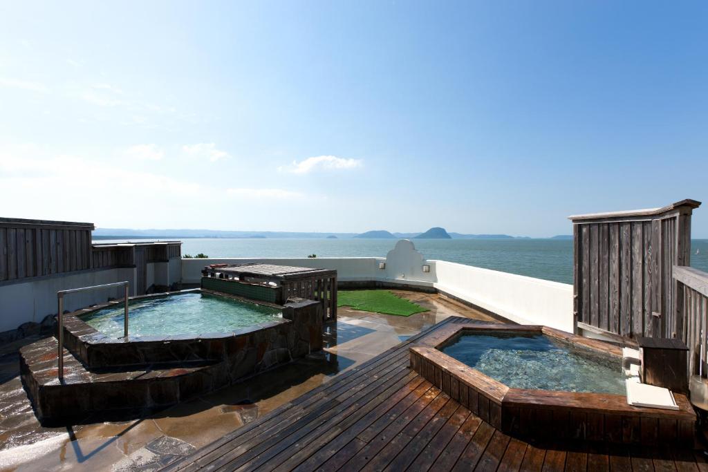 - une terrasse avec 2 bains à remous au-dessus d'une maison dans l'établissement Hotel Uohan, à Karatsu