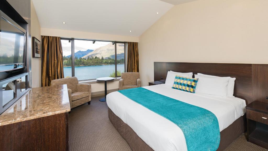 a hotel room with a bed and a large window at Copthorne Hotel & Resort Lakefront Queenstown in Queenstown