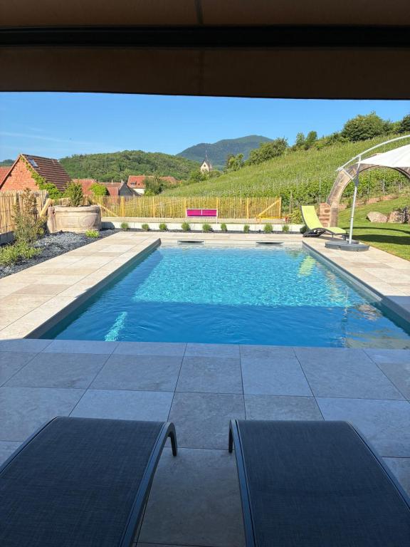a swimming pool with two chaise lounges on a patio at Gite Haydi in Itterswiller