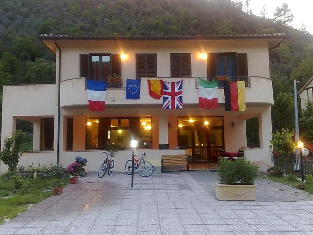 a house with flags hanging in front of it at Hotel Ristorante Umbria Valnerina in Vallo di Nera