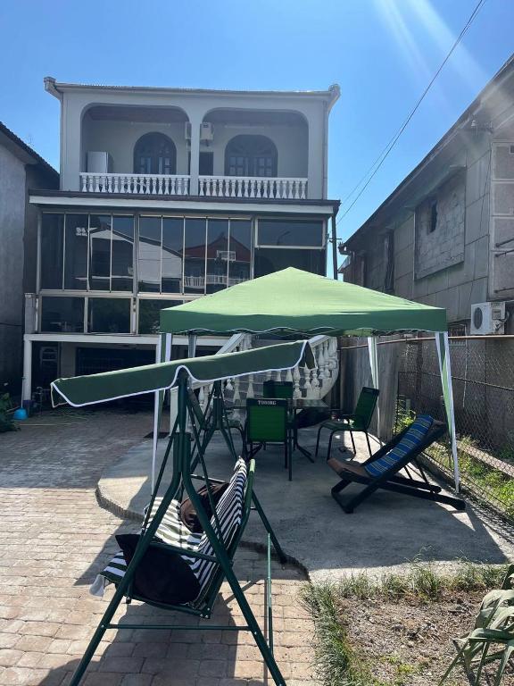 a swing set with a green umbrella and chairs at Chavchavadze 56 in Kobuleti