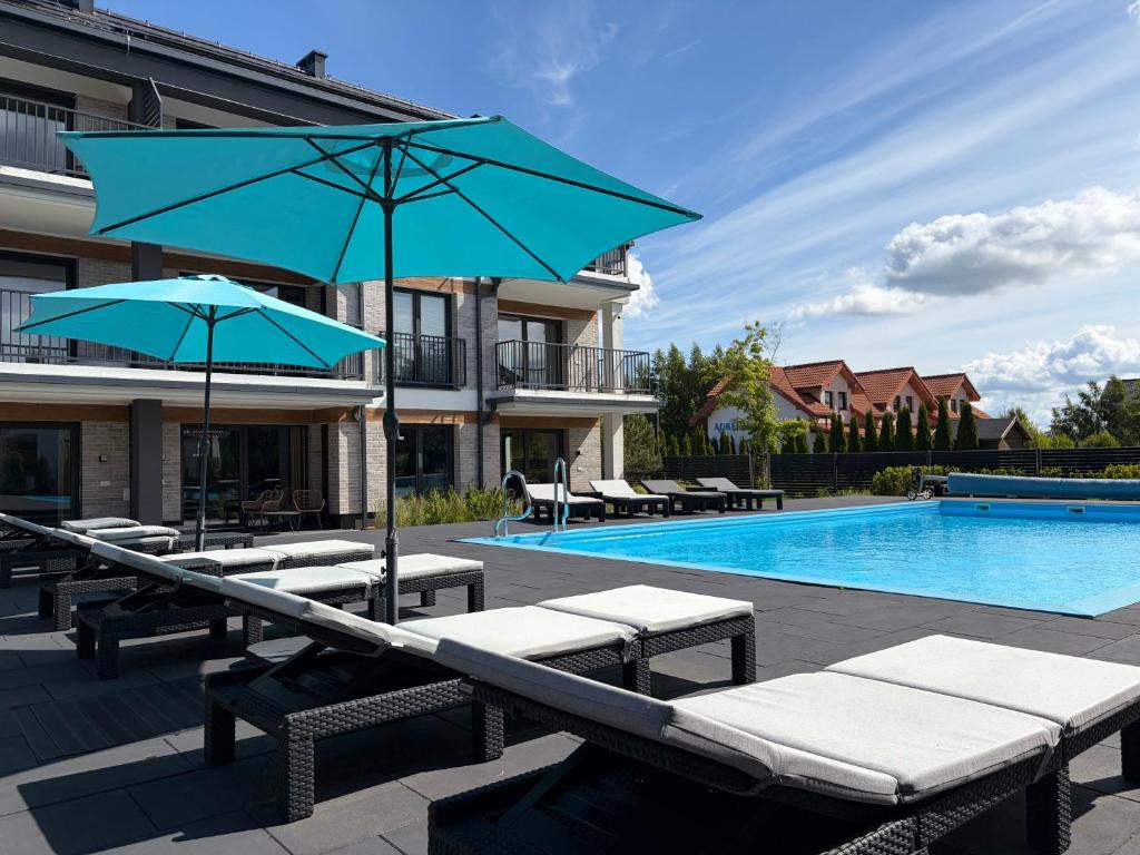 a swimming pool with chairs and umbrellas next to a building at Inny Klimat in Rowy