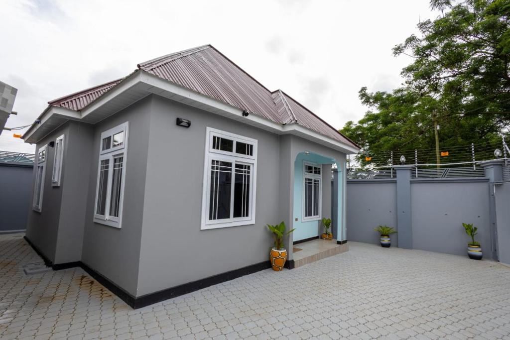 a small white and blue house with a fence at Akibo Residency Apartment in Mwanza