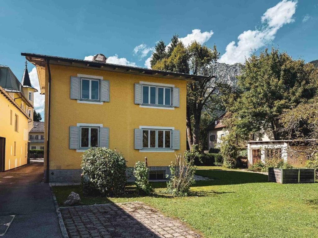 a yellow house with windows and a yard at Doras Ferienhaus in Bad Reichenhall