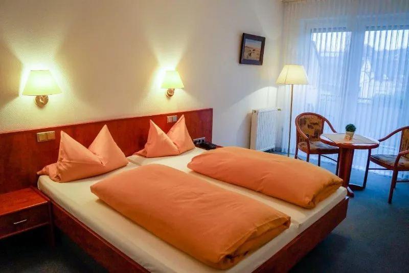 a hotel room with a bed with orange pillows at Hotel Bonke in Nordhorn