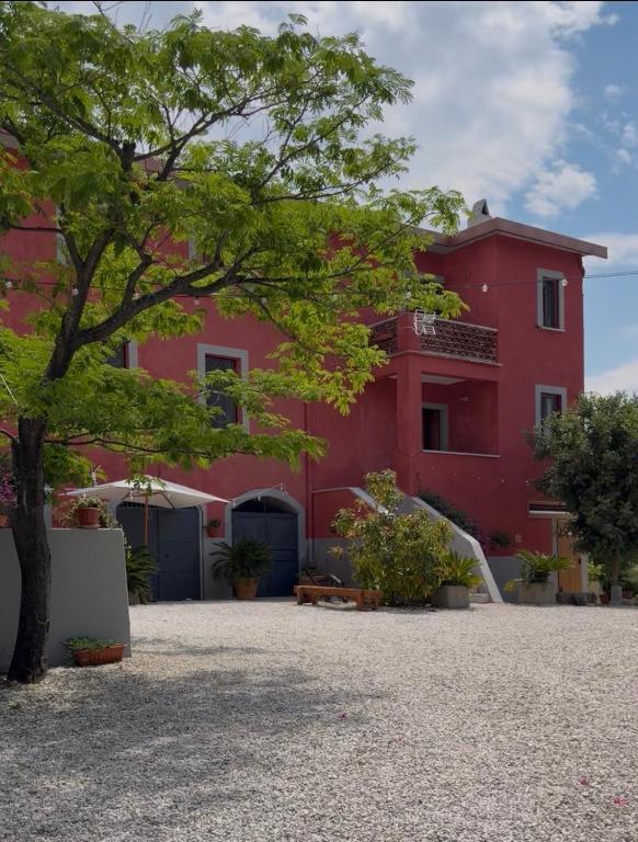 a red building with a tree in front of it at Tenuta degli Ulivi - Dimora Contadina in Montecorvino Rovella
