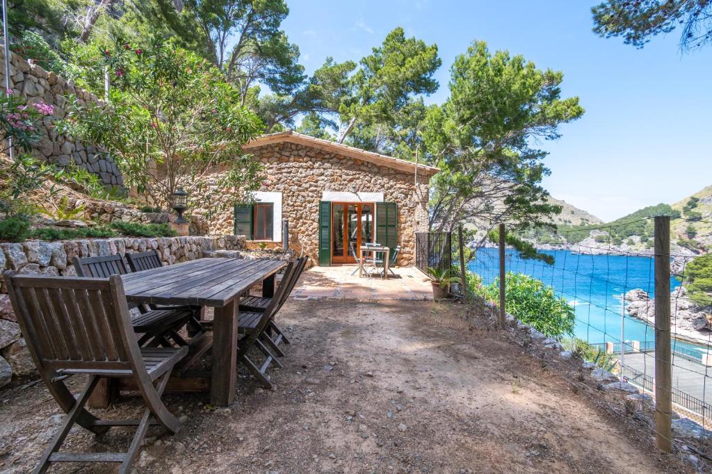 a stone cottage with a wooden table and chairs at Casita Sa Calobra in Cala Tuent