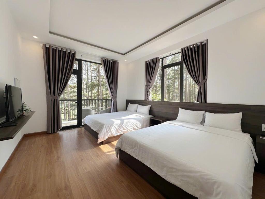 a bedroom with two beds and a tv and windows at Mimosa Forest Hotel Villa in Xuan An