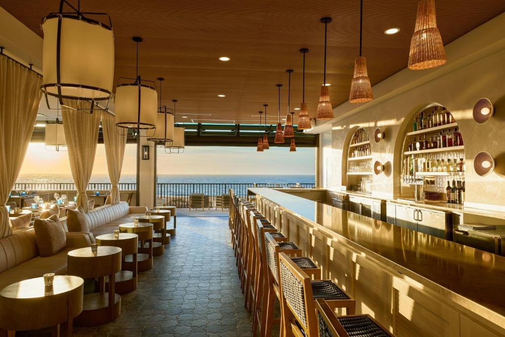 a restaurant with a bar with the ocean in the background at Ashore Oceanfront Hotel by Marriott in Ocean City