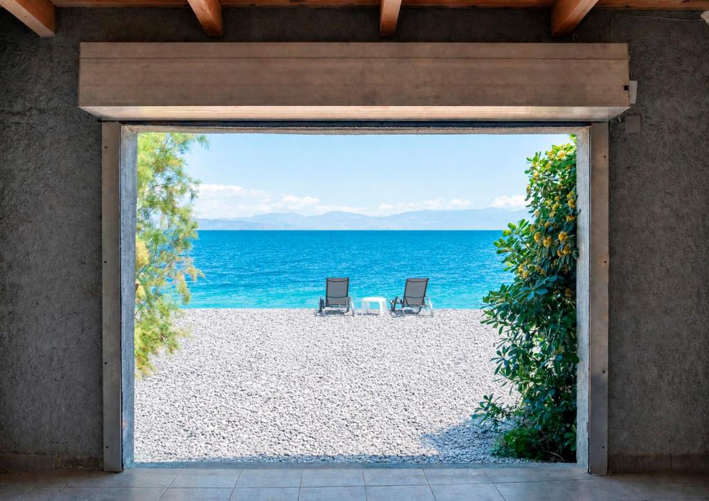 an open door to the beach with two chairs at Villa Dorianna in Egira