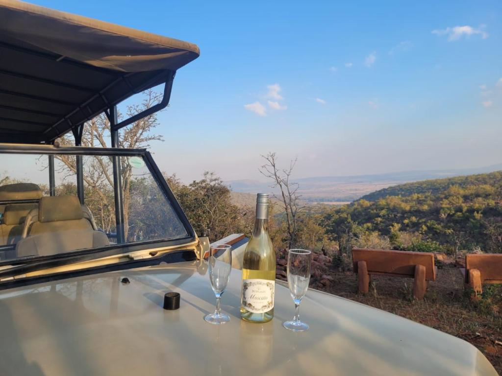 a bottle of wine sitting on a table with two glasses at Kunkura Game Lodge & Conference Centre in Modimolle