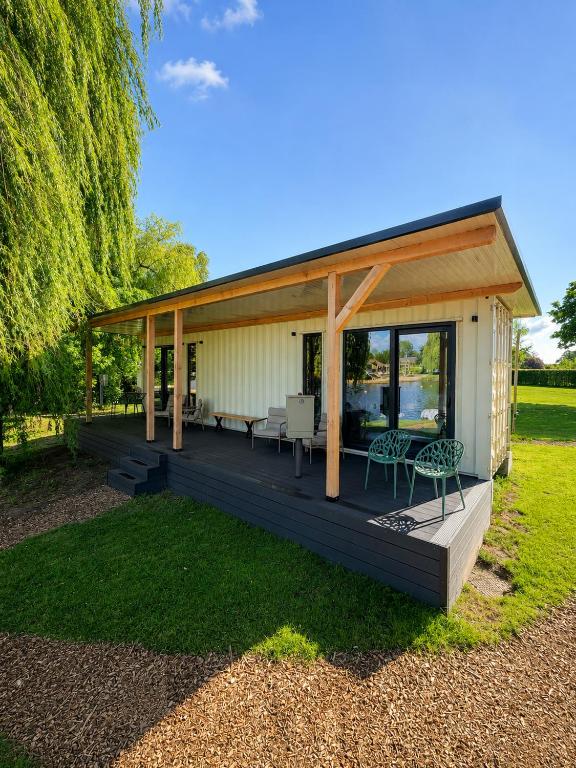 a house with a large wooden deck with chairs at Luxury Lake Cabin in Alphen