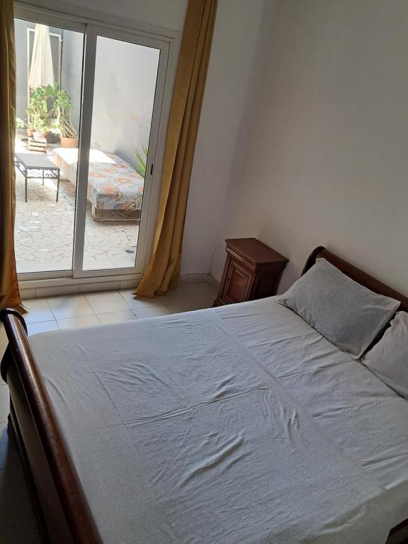 a bedroom with a bed and a large window at Rdc in Ouakam
