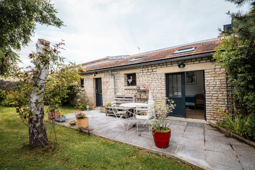 a brick house with a patio with a table and chairs at P'tite Maizoun - Gîte in Hermanville-sur-Mer