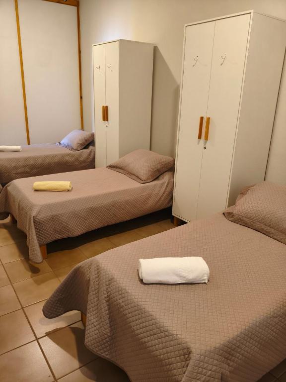 a room with three beds and cabinets with towels on them at Flats Rio Branco in Uberaba