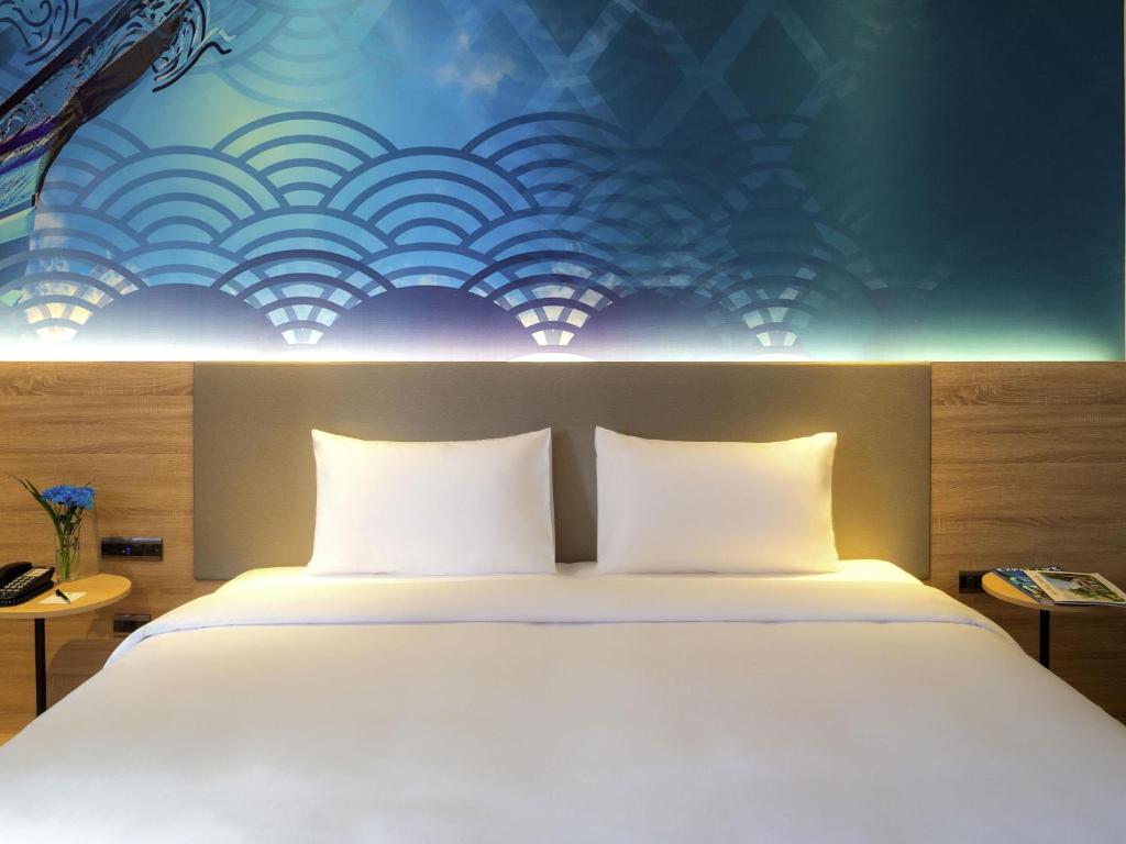 A close view shows a large white bed against a blue patterned feature wall.