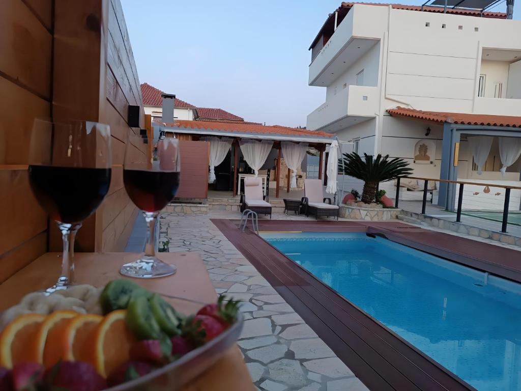 a table with wine glasses and a bowl of fruit next to a pool at Local Paradise Xilokastro in Xylokastro