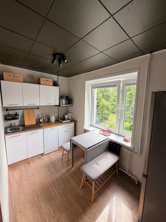 a kitchen with white cabinets and a table and a window at Kauguri apartment residence in Jūrmala