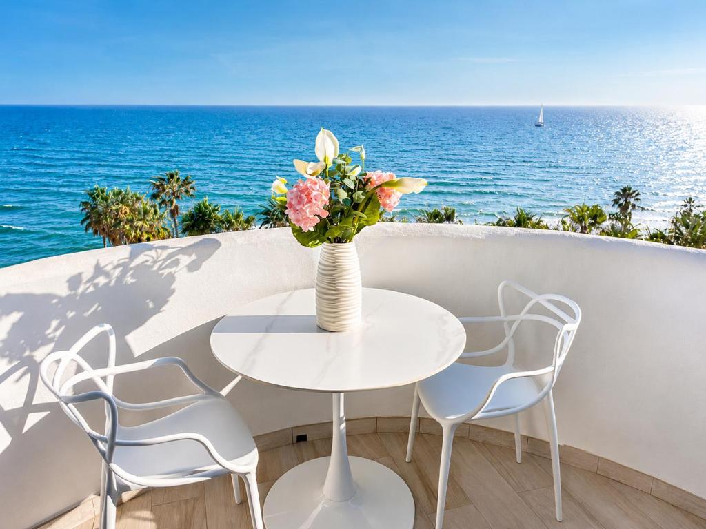 a table with a vase of flowers on a balcony with the ocean at Apartamento Algaida Calahonda in Sitio de Calahonda