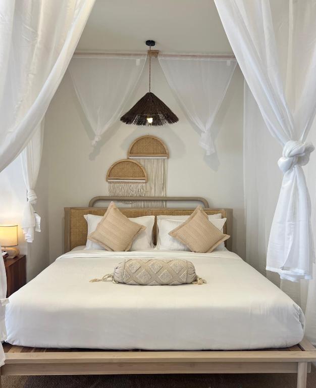 a bedroom with a white bed with white curtains at Nomad Beach House, Koh Lanta in Ko Lanta
