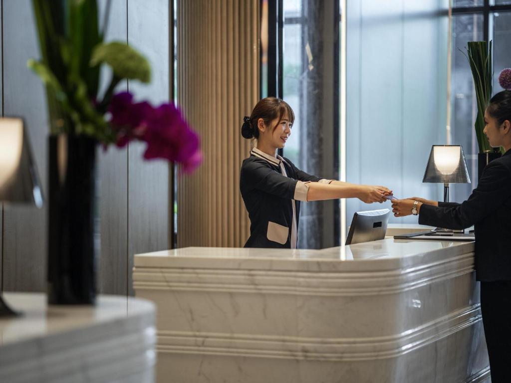 a woman shaking hands with a man at a desk at Pullman Suzhou Zhonghui in Suzhou