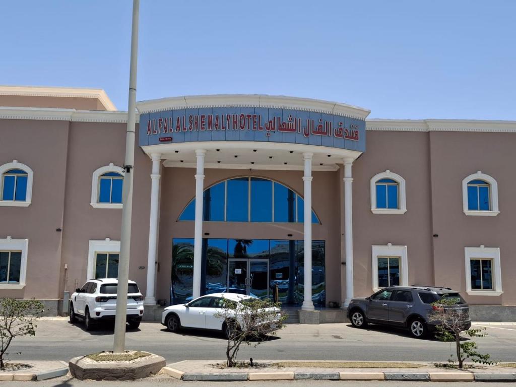 a building with cars parked in a parking lot at فندق الفال الشمالي الفندقية in Ḑubā