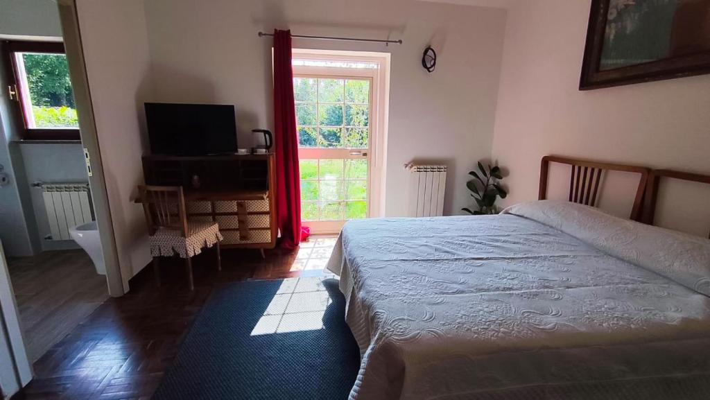 a bedroom with a bed and a television and a window at La Caldara House in Manziana