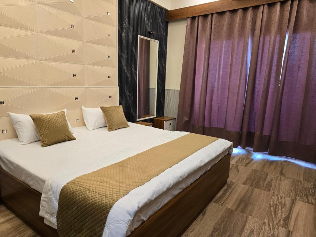 a bedroom with a large bed with purple curtains at Siri Stays in Greater Noida