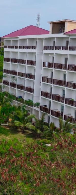 a tall white building with a red roof at Malika Blue Hotel Nungwi, Zanzibar in Banda Kuu