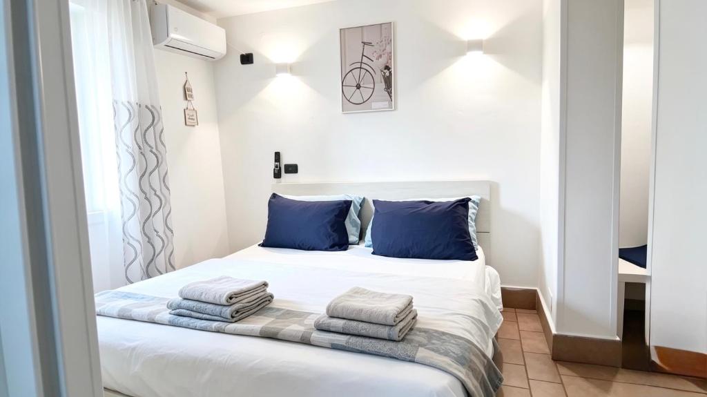 a bedroom with a white bed with blue pillows at Lighthouse Taranto in Taranto