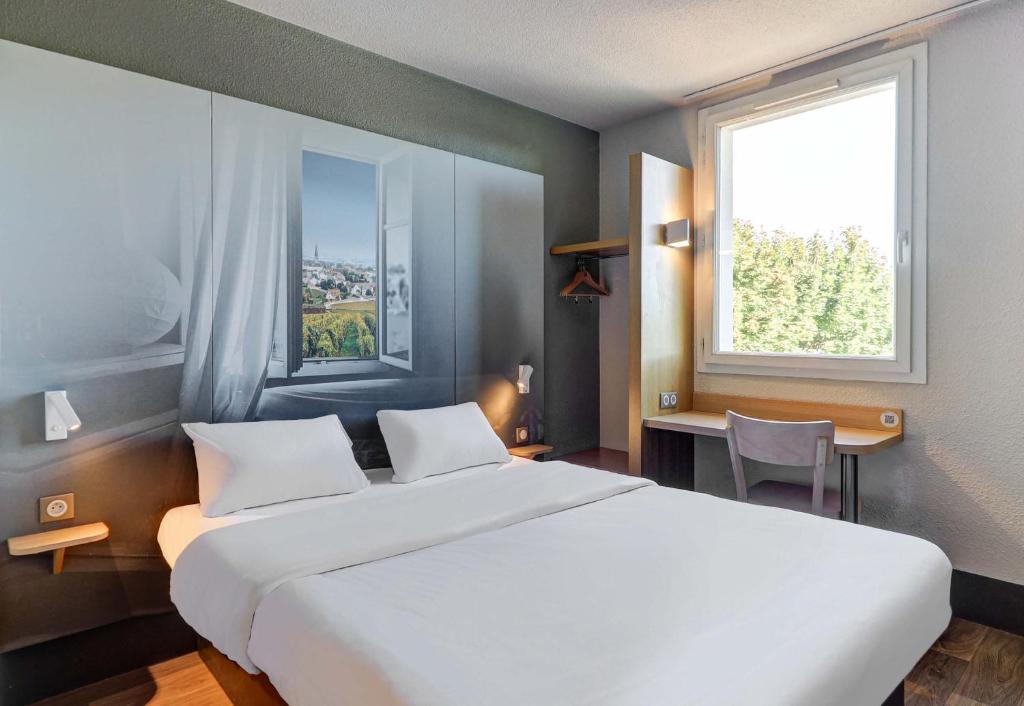 a bedroom with a large white bed and a window at B&B HOTEL BEAUNE Nord in Savigny-lès-Beaune