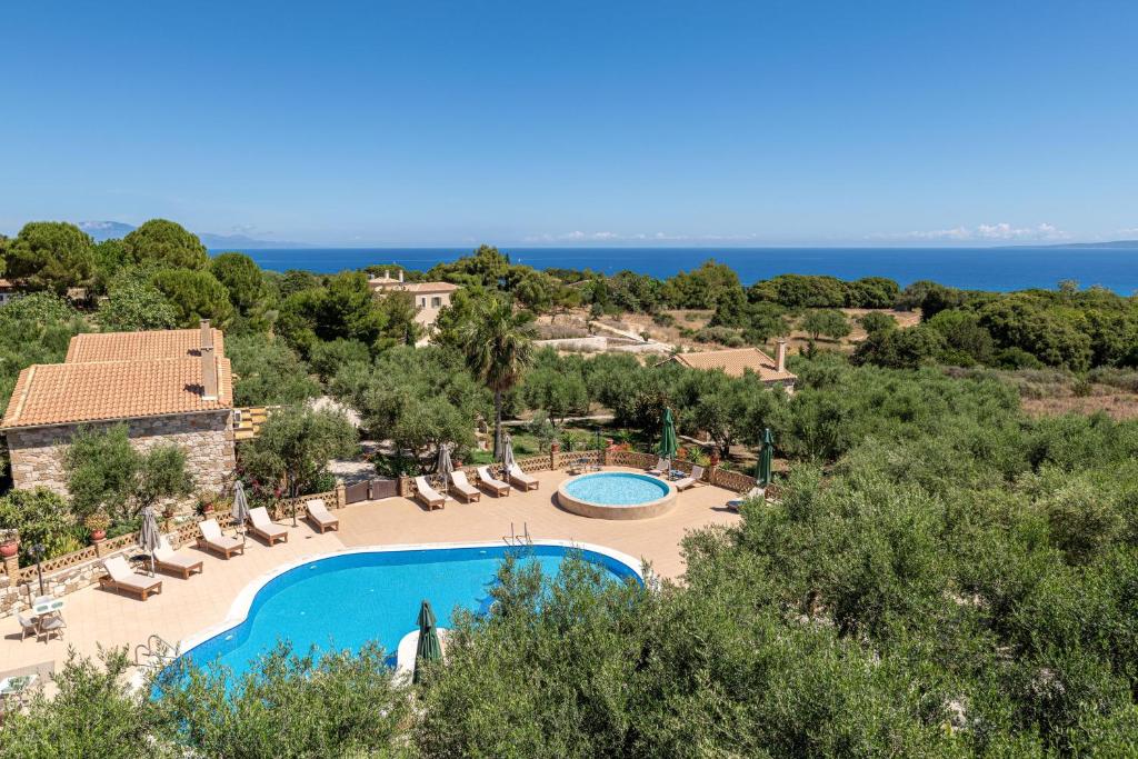 a resort with two pools and chairs and the ocean at Joanna's Stone Villas in Vasilikos