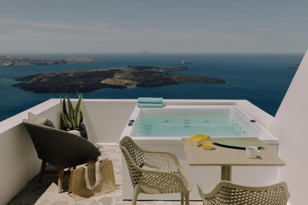 a hot tub on a balcony with a table and chairs at Agave Santorini Design Boutique Hotel in Imerovigli