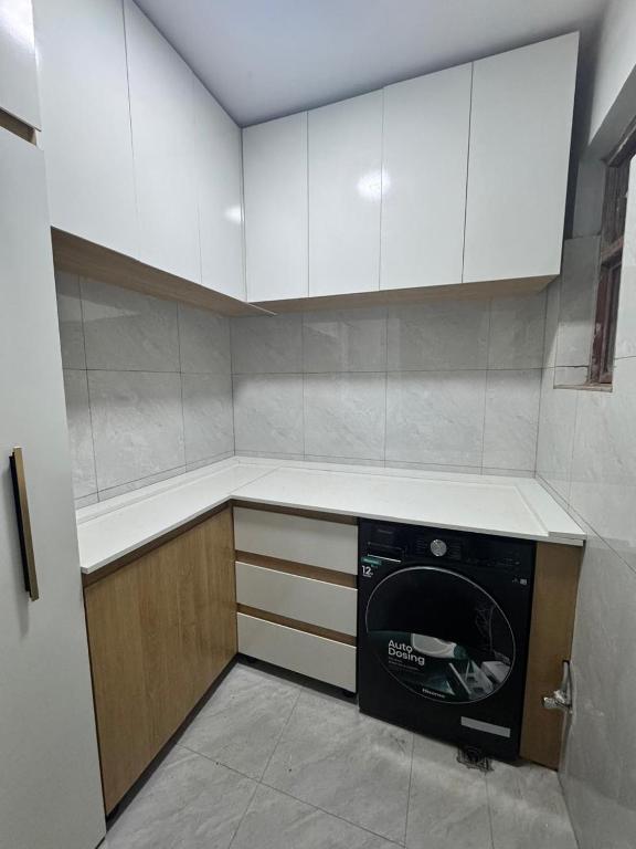 a kitchen with white cabinets and a black dishwasher at The Moon Apartment in Kigali