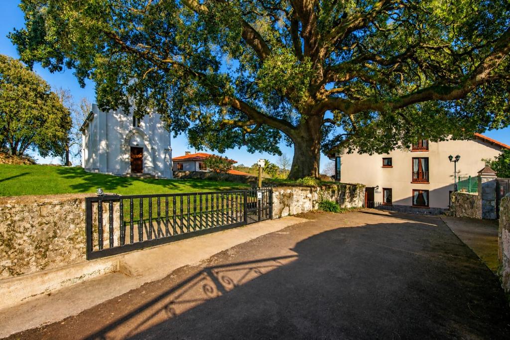 a tree and a fence in front of a house at Llanes Casa cerca Playa y Centro – Encina Pancar in Pancar