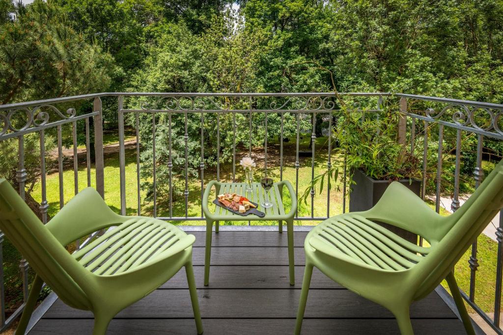 two green chairs and a table on a deck at Logis Hôtel Restaurant Les 2 Rives - CHAMBRES CLIMATISEES - A75, en bordure de rivière in Banassac