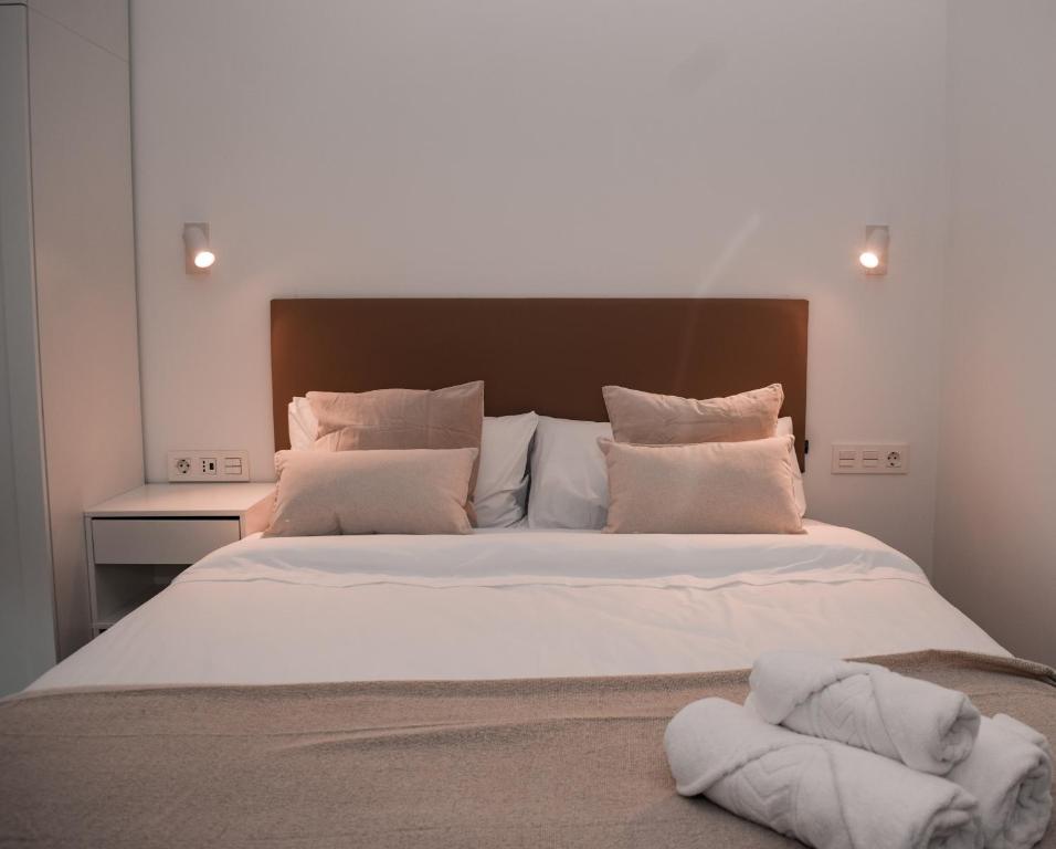 una camera da letto con un grande letto con lenzuola e cuscini bianchi di NIDOM experience a Madrid