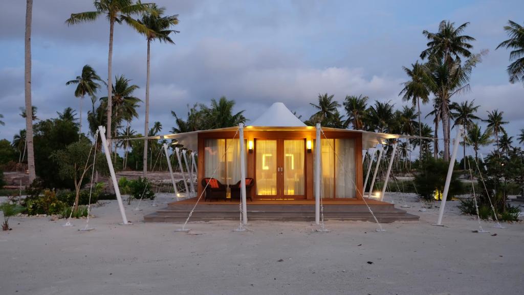 a small building on the beach with palm trees at Marahai Villa Morotai in Dehegila