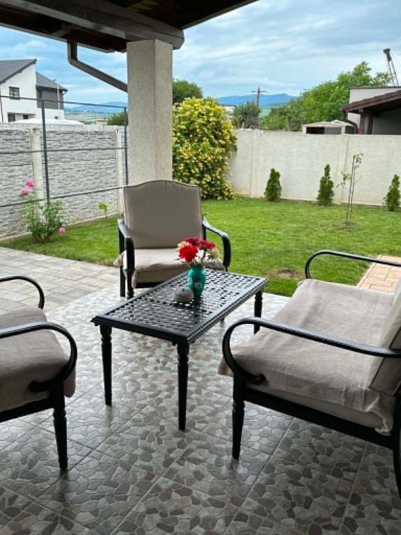 a patio with two chairs and a table with a vase of flowers at Casa Carolina in Alba Iulia
