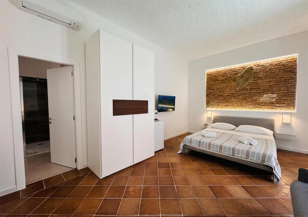 a bedroom with a bed and a brick wall at Isuleddu Room & Stairs in La Maddalena
