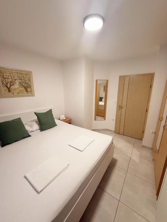 a bedroom with a large white bed with green pillows at Sobe Šušanj in Karlobag