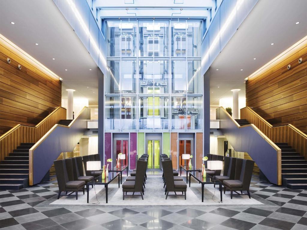 a lobby with chairs and tables and stairs at MÖVENPICK Hotel Stuttgart Airport in Leinfelden-Echterdingen