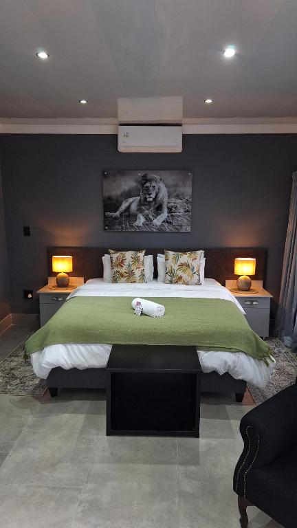 a bedroom with a large bed with a green blanket at Lion Lodge in Bloemfontein