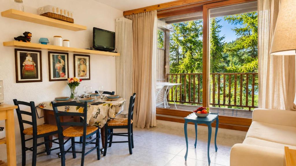 a dining room with a table and chairs and a large window at Hostdomus - Lumiere Apartment R15 in San Sicario